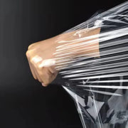 Close up of a closed fist trying to puncture clear pallet wrap and stretching it instead