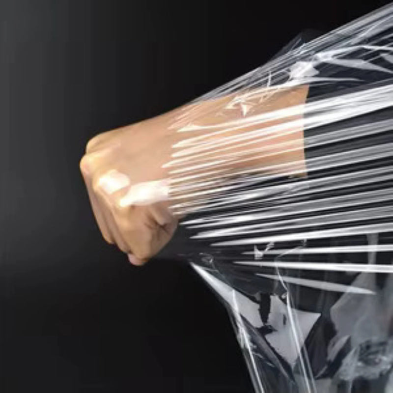 Close up of a closed fist trying to puncture clear pallet wrap and stretching it instead