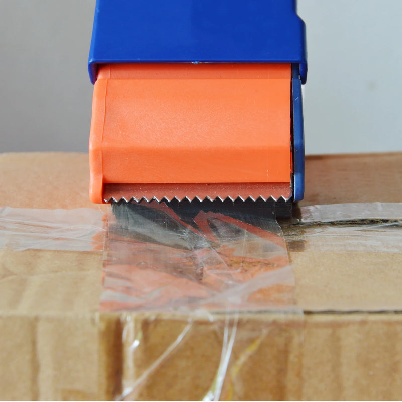 closeup of a cardboard box being sealed with clear sealing tape using a tape dispenser