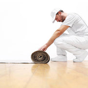 man unrolling a roll of corrugated cardboard on a floor