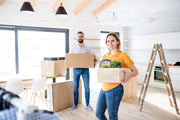 Man and woman with full cardboard boxes in a new home suggesting they have just moved house