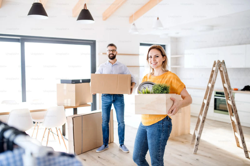 Man and woman with full cardboard boxes in a new home suggesting they have just moved house