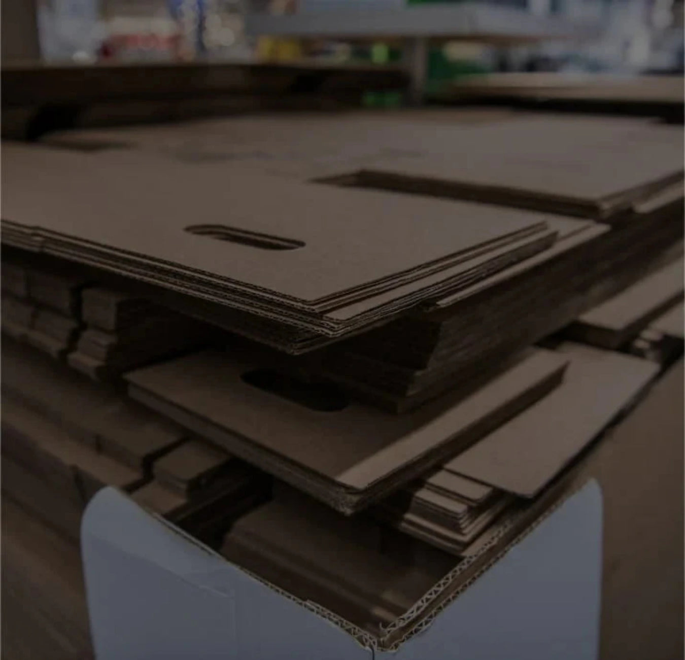 Stack of unassembled flatpacked cardboard boxes on a white surface with a blurred background