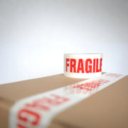 a roll of fragile tape on top of a cardboard box that is sealed with fragile tape