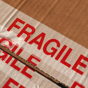 closeup of a cardboard box that was sealed with multiple layers of fragile tape but has now been opened