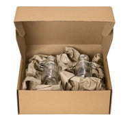 Cardboard box with glass jars wrapped in paper on a white background
