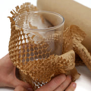 a wine glass being wrapped in protective honeycomb paper suggesting that it will be going into storage