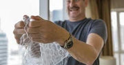 Man bursting the bubbles of clear bubble wrap with a blurred indoor background