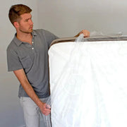 A man covering a mattress with a plastic mattress bag