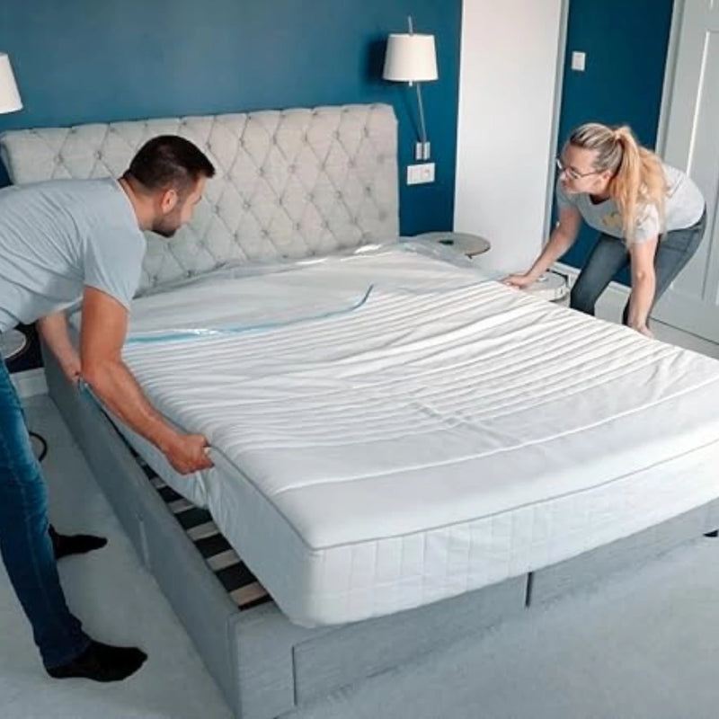 a couple wrapping a double mattress with a mattress bag in an empty bedroom