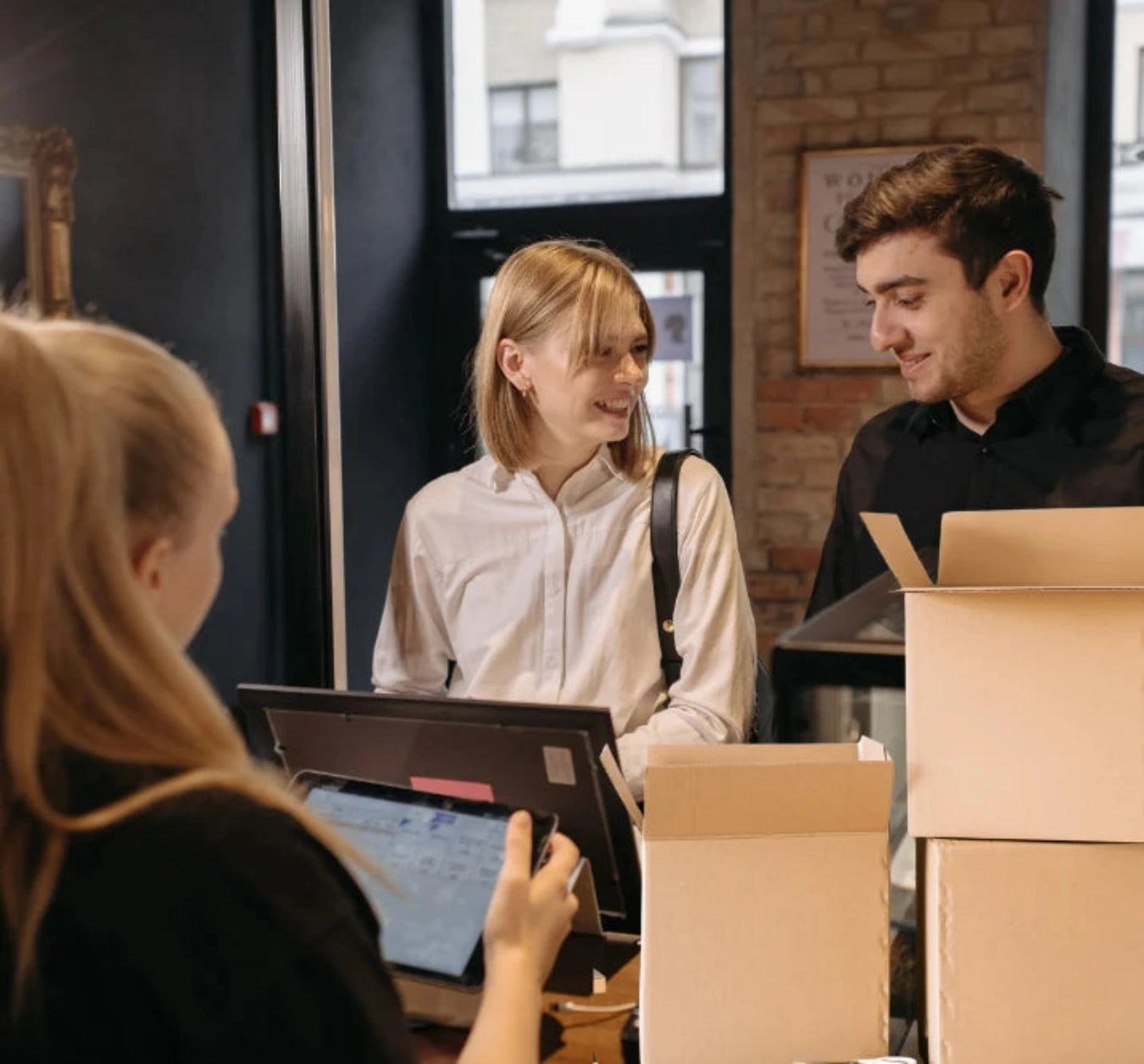 People in a shop with cardboard moving boxes, possibly moving and packaging items.