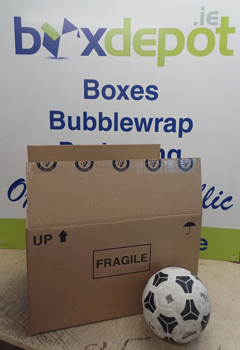 A large once-used preloved double walled cardboard box beside a football in front of Box Depot advertisement