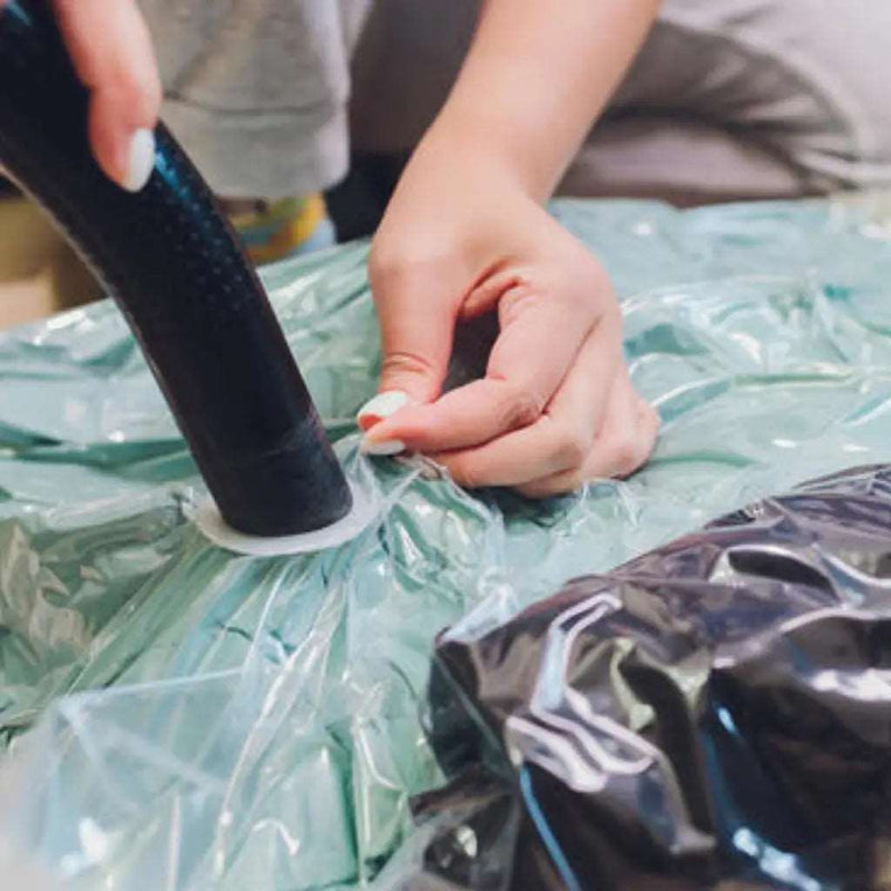 closeup of a woman using a vacuum cleaner to take the air from a filled vacuum storage bag