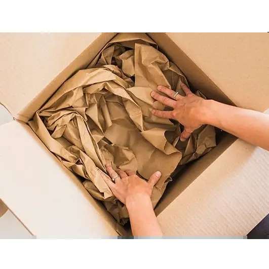 hands putting paper voidfill into a cardboard box