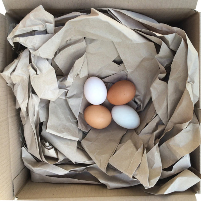 a cardboard box filled with paper voidfill and four hens eggs suggesting how protective paper voidfill is