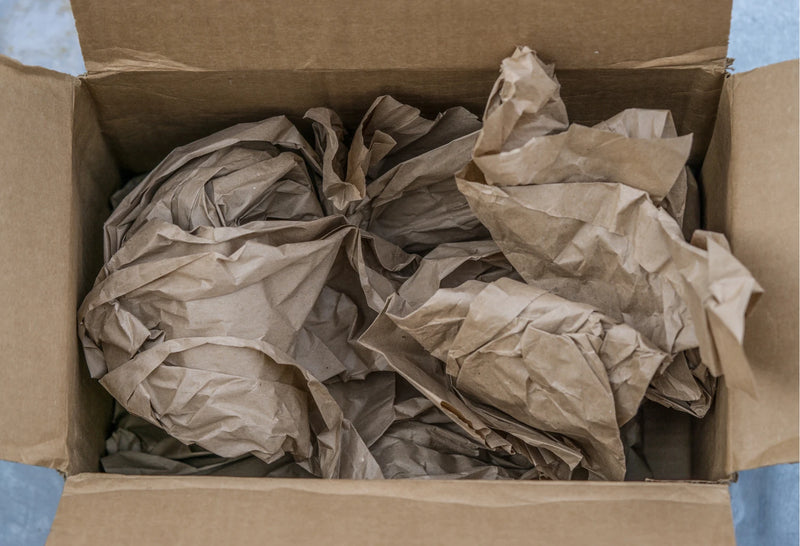 Cardboard box filled with crumpled brown paper voidfill.