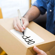 person writing "office" with a black marker on a white label that is stuck to a cardboard box