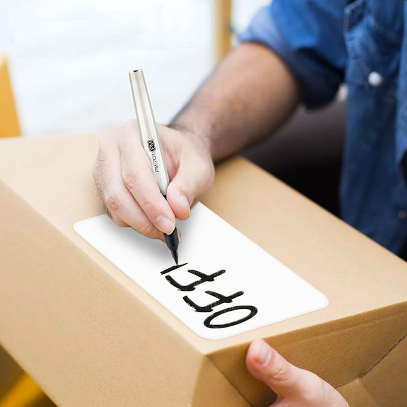 person writing "office" with a black marker on a white label that is stuck to a cardboard box