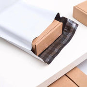 open white mailing bag showing a small cardboard box on a desk