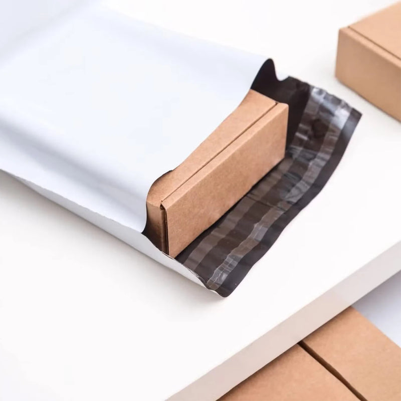 open white mailing bag showing a small cardboard box on a desk