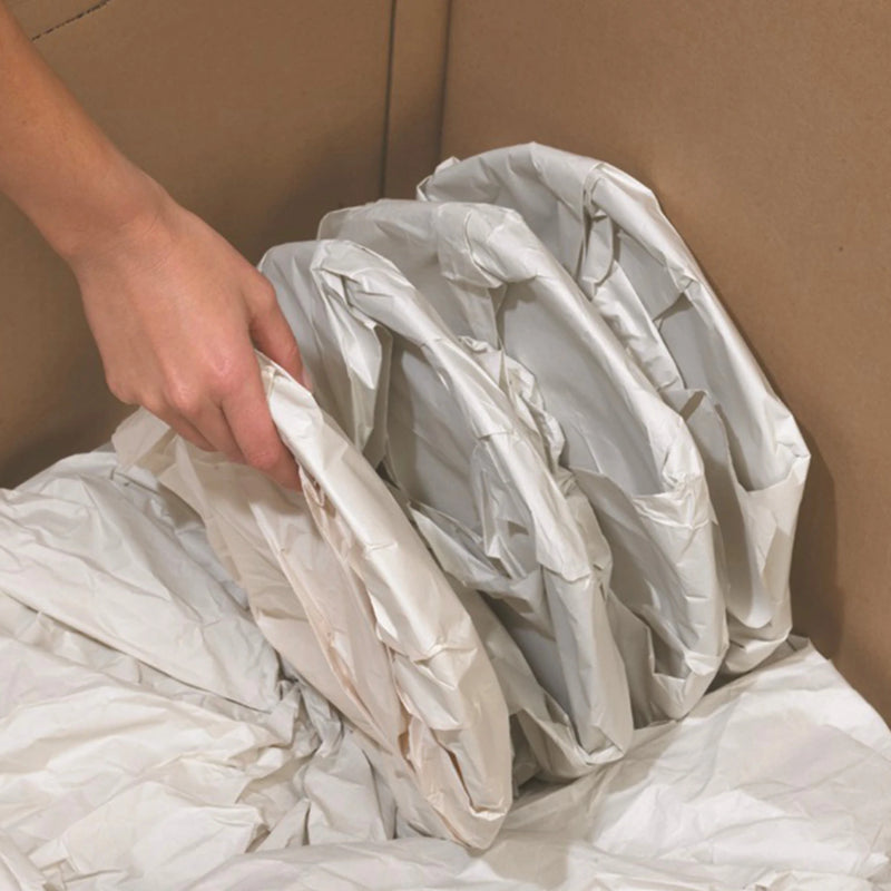plates wrapped in white packing paper being stacked into a cardboard box