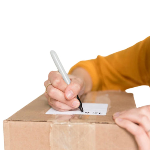 a hand writing a label on a cardboard box with a black marker on a white background
