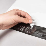 a hand removing the peel-and-seal strip from a white mailing bag